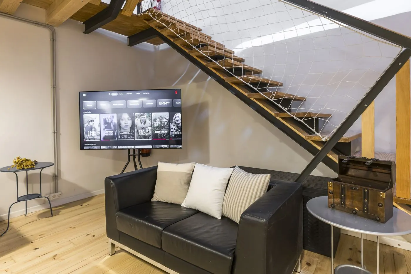 Rincón con sofá y televisión junto a la escalera